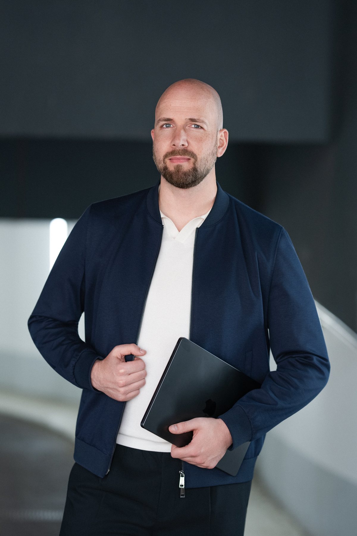 René Wienhold aufrecht auf einer Betonrampe, Laptop unter dem Arm