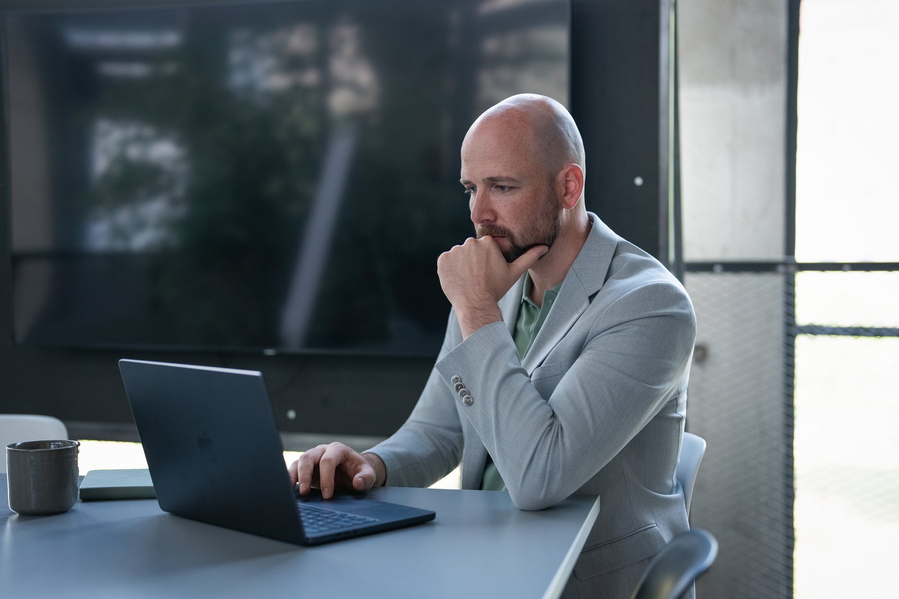 René Wienhold konzentriert am Laptop vor einer Fensterfront