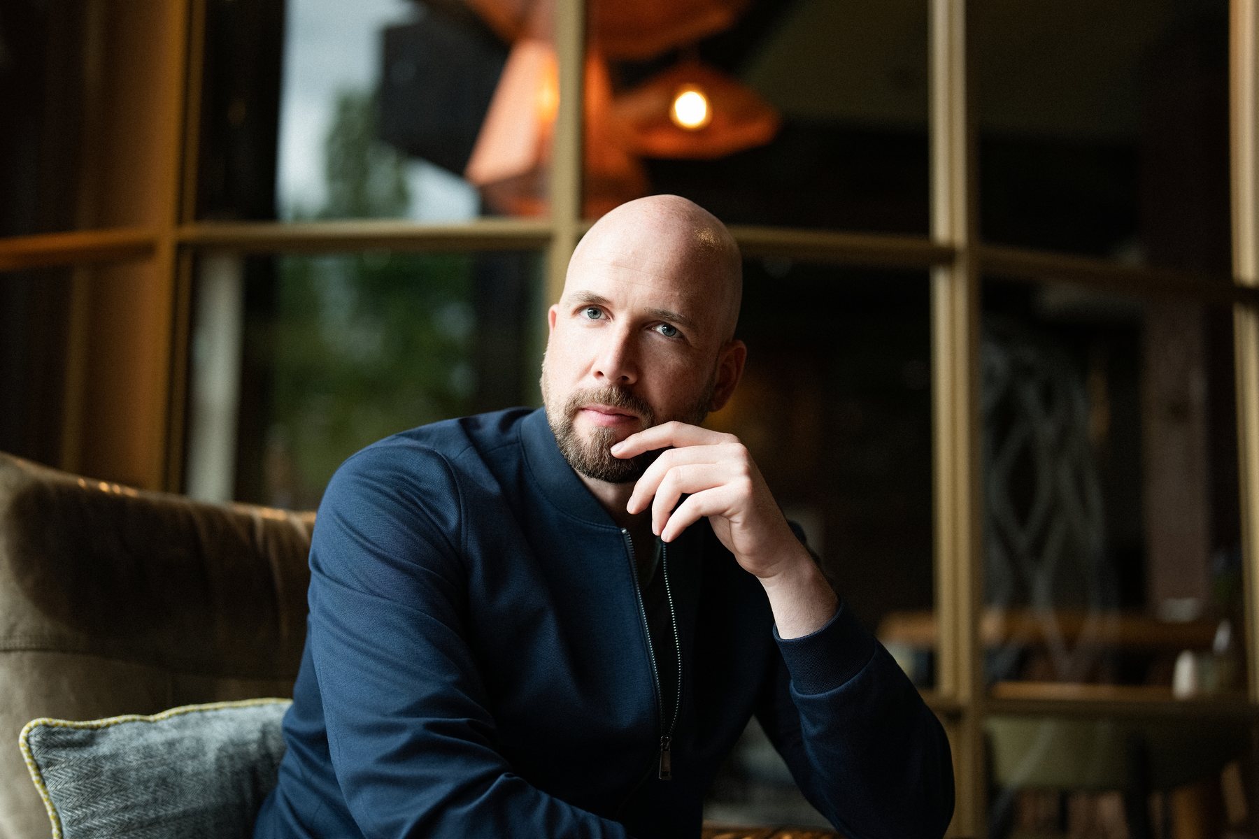 René Wienhold im Sessel, Hand am Kinn, nachdenklich