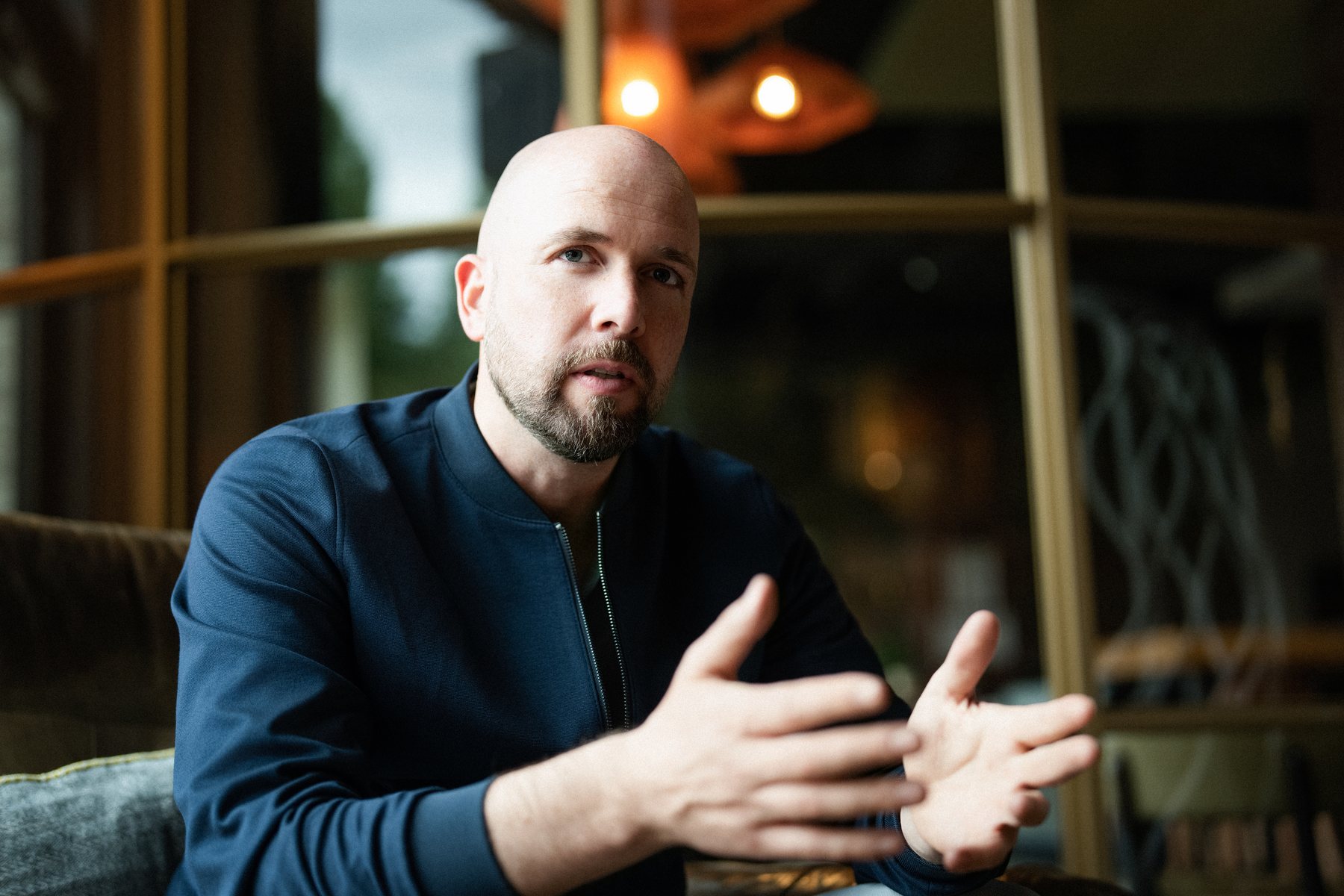 René Wienhold im Gespräch, offene Handbewegung, warmes Licht