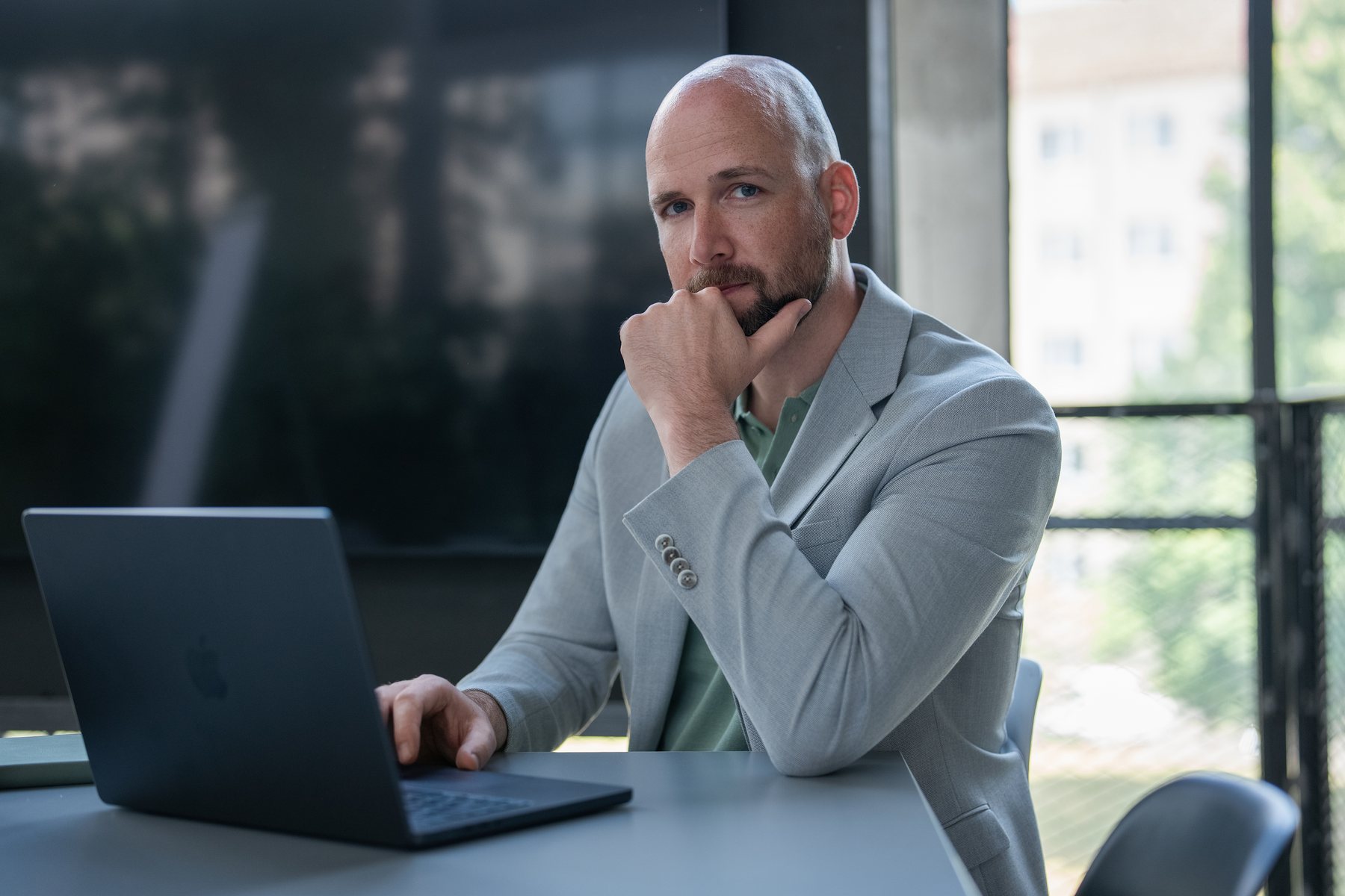 René Wienhold am Laptop, Hand am Kinn, Fensterlicht